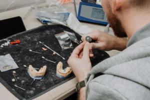 Dental professional holding an implant-supported full-arch denture model, representing top US dental labs