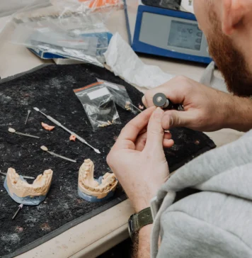 Dental professional holding an implant-supported full-arch denture model, representing top US dental labs
