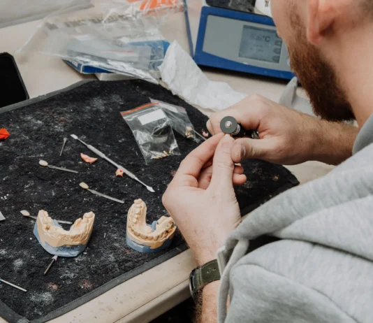Dental professional holding an implant-supported full-arch denture model, representing top US dental labs